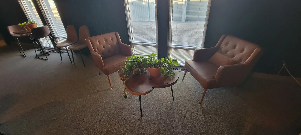Armchairs and a live-edge table beside the Cafe Room windows