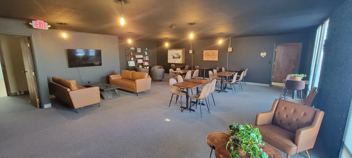 The Cafe Room with leather couches, a wall-mounted TV, cafe tables and pendant lighting